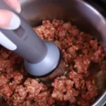 گوشت کوب برقی در حال له کردن گوشت و غذای داغ